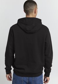 Sudadera con capucha negra, confeccionada en una mezcla de algodón. Cuenta con un bolsillo canguro y puños y dobladillo acanalados. Corte casual con un diseño sencillo.