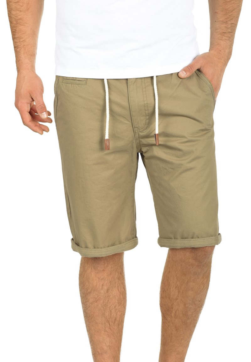 Khaki shorts laget av bomullsblanding, med snøring i livet, rull opp ermer og sidelommer. Glatt tekstur hele veien.
