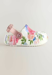 Zoccolo bianco con stampa floreale multicolore e cinturino regolabile sul tallone in metallo color oro rosa su sfondo uniforme.