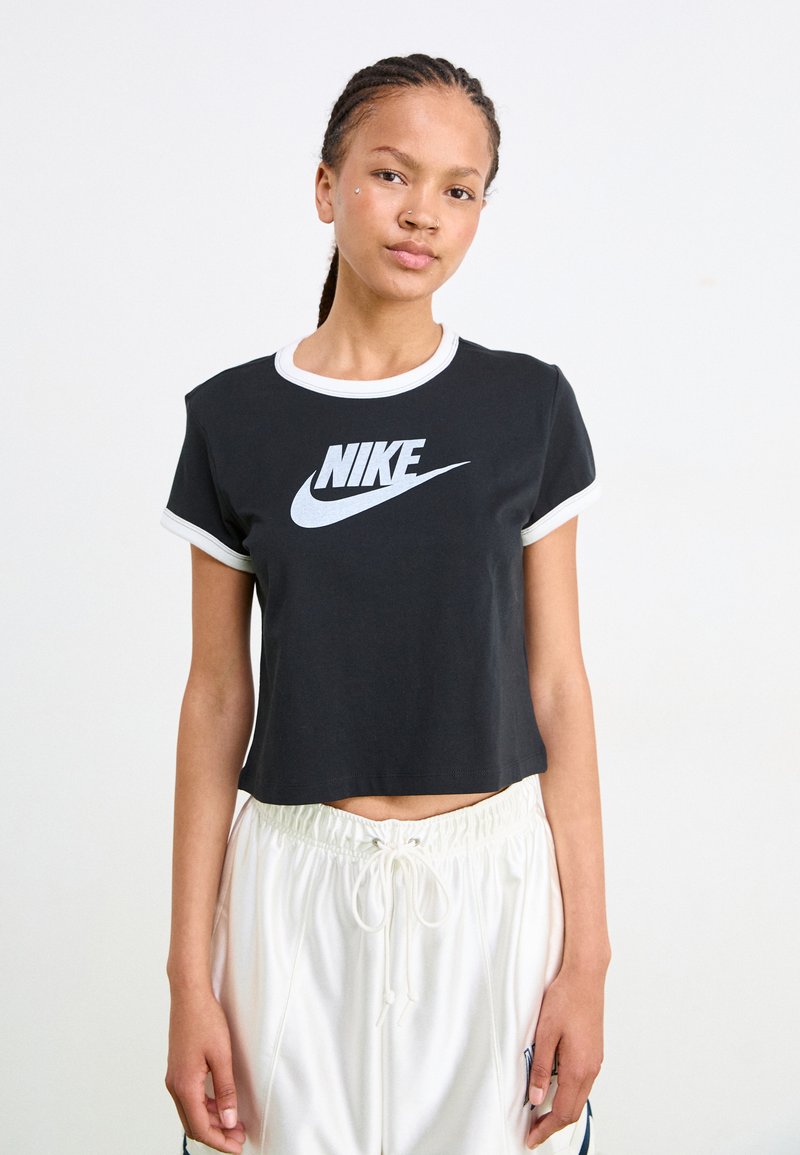 Fekete rövid ujjú, fehér szegéllyel ellátott póló, amelyen a mellkas közepén egy hangsúlyos fehér Nike logó található. Rövid ujjakkal és puha pamut anyagból készült.