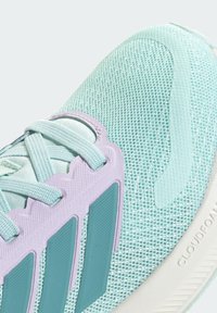 Svetlo tyrkysová bežecká obuv s hornou časťou zo sieťoviny, textúrovanými detailmi, pletenými šnúrkami a vzorovanou podrážkou s výrazným logom.