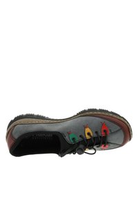 Chaussure en suède gris avec une semelle en caoutchouc noir, ornée d'accents colorés en jaune, vert et rouge, et d'un design unique sans lacets pour un maintien sûr.