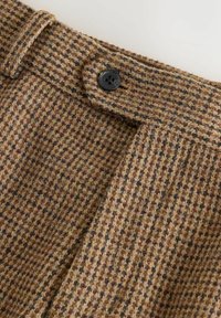 Brown checked trousers made of textured fabric, featuring a black button closure and a visible waistband with belt loops.