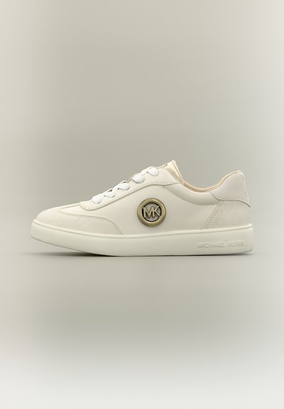 Λευκό sneaker χαμηλού τύπου με στρογγυλό χρυσό λογότυπο MK στο πλάι, λευκά κορδόνια και επωνυμη σόλα σε ουδέτερο φόντο.