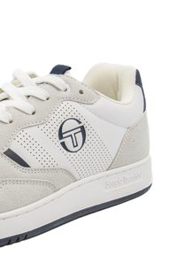 Lichtgrijze suede en witte leren sneaker met geperforeerd ontwerp, vetersluiting en marineblauwe accenten. Bevat "Sergio Tacchini" branding.