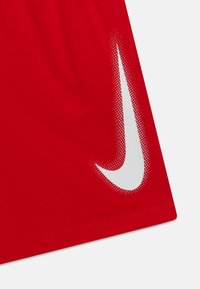 Camisa deportiva roja con un logo de Nike en forma de swoosh blanco y punteado en la parte inferior derecha. Hecha de una tela suave y transpirable.