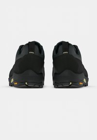 Fekete túracipő texturált felsőrésszel, Vibram talppal, megerősített sarokkal és húzószalaggal, masszív kialakítással a tartósság érdekében.