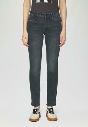 Front view of slim-fit dark grey jeans worn with black and white sneakers on a person standing against a plain background.