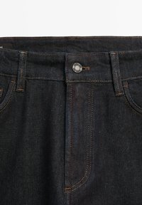 Ciemnoniebieski pas do dżinsów z denimu z metalowym guzikiem, szlufkami na pasek i widocznym pomarańczowym szwem.