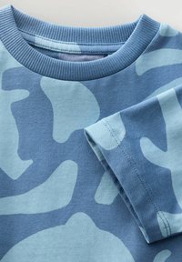 Camiseta de algodón azul con un patrón abstracto en azul claro, cuello redondo acanalado y mangas cortas con dobladillos cosidos.