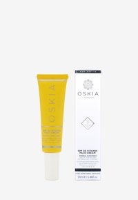 Gul tub av SPF 30 vitamin ansiktskräm med vit kapsyl, märkt "OSKIA LONDON", tillsammans med en vit låda med liknande varumärkning och detaljer.