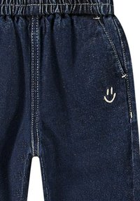 Joggers in denim scuro con vita elastica, caratterizzati da un ricamo di una faccina sorridente in bianco sulla tasca anteriore e cuciture a contrasto.