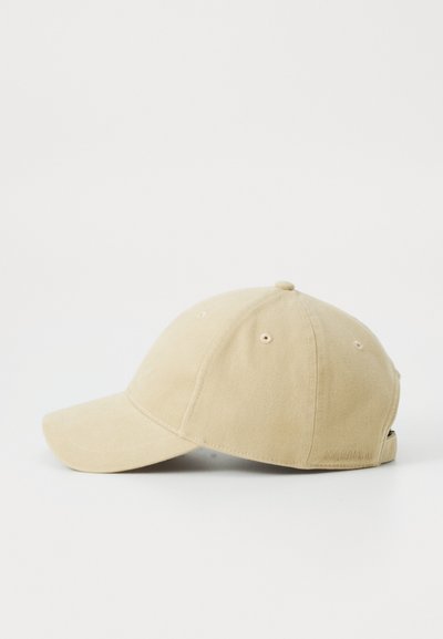 Beige baseball cap made of cotton with a curved visor, six ventilation eyelets, and a small logo detail on the side.