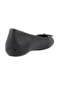 Zapato plano negro que combina cuero liso con tejido texturizado. Punta redonda con un detalle mínimo y un pequeño lazo decorativo.