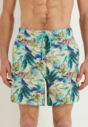 Shorts de bain en beige clair avec des motifs de feuilles tropicales vertes et bleues vives et des accents floraux roses. Dotés d'une taille avec cordon de serrage.