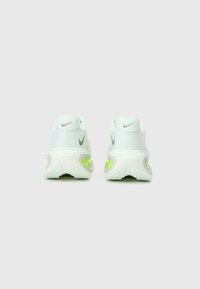 Baskets Nike blanches et vert clair avec une tige en mesh, un talon arrondi et des accents verts. Dotées d'une semelle texturée pour une meilleure adhérence.