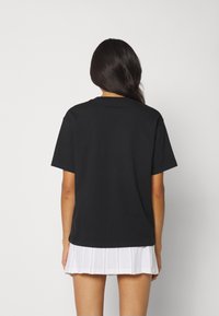 T-shirt in cotone nero con un fit rilassato, maniche corte e scollo a giro, abbinato a una gonna bianca plissettata.