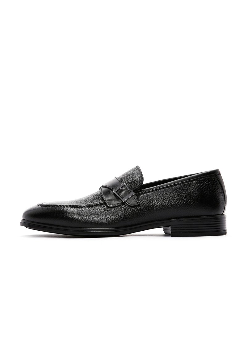 Zwarte leren loafers met een gestructureerde afwerking, voorzien van een band met een gespsierraad, lage hak en afgeronde neus.