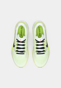 Baskets de running Nike en mesh jaune vif et blanc, dotées de lacets noirs et d'un logo swoosh noir. Semelle légère avec accent orange.