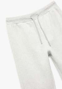 Hellgraue Sweatpants aus einem weichen Baumwollmix, mit elastischem Bund und Kordelzug sowie seitlichen Taschen, glatte Textur.