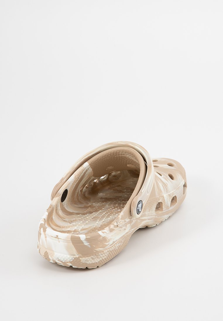 Zueco beige con estampado, tipo slip-on, que presenta orificios de ventilación, un interior texturizado y un acento de logo circular en el lado exterior. Material suave.