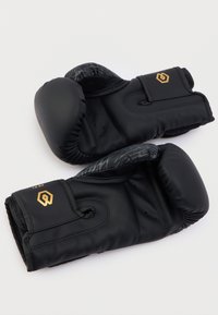 Μαύρα γάντια πυγμαχίας με επένδυση στα ροκανίδια, λείο συνθετικό υλικό, χρυσές λεπτομέρειες με λογότυπο και υφή σχεδιασμού στον καρπό. Ασφαλές κλείσιμο με γάντζο και θηλιά.