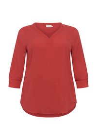 Blouse rouge à manches trois-quarts avec un col en V, fabriquée en tissu lisse, présentant un ourlet légèrement courbé et des détails de couture subtils.