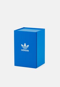 Boîte en carton bleu avec un couvercle plat, présentant un logo Adidas trefoil blanc sur le devant. Texture lisse, forme rectangulaire.
