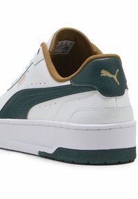 Białe sneakersy z fakturowanym zielonym skórzanym akcentem, złotym logo i brązowym wnętrzem. Gruba biała podeszwa z wzorzystym bieżnikiem.