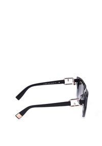 Lunettes de soleil noires avec des branches épaisses et des détails métalliques, vues de côté sur fond blanc.