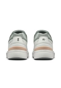 Witte en lichtgrijze sport schoenen met een geprofileerde mesh bovenwerk, roze accent op de hiel en een dikke rubberen zool met een patroon voor grip.