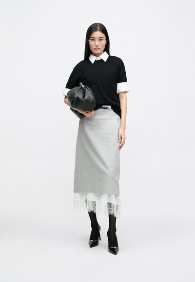 Black sweater with white collar, gray skirt with lace hem, black handbag, black tights, and pointed heels in a neutral background.