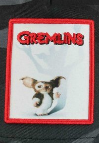Embroidered patch featuring a cartoon gremlin with large ears and wide eyes, framed in a red border on a black fabric background.