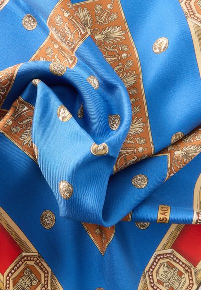 Μπλε και κόκκινο μεταξωτό ύφασμα με περίτεχνα χρυσά σχέδια, συμπεριλαμβανομένων μεταλλίων και φυλλωτών μοτίβων, draped και τσαλακωμένο σε πτυχώσεις.