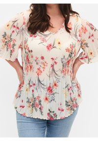 Blusa a pieghe con motivo floreale in crema, maniche a farfalla corte, con dettagli in rosa, giallo e verde. Scollo a V e design fluido.