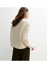 Maglione spesso in maglia creativa con un motivo testurizzato, scollo rotondo e maniche lunghe. L'orlo è leggermente arrotondato, offrendo una vestibilità rilassata.