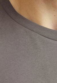 Grå bomulds T-shirt med rund hals, fin ribbet krave og glat tekstur, der viser lette variationer i stoftykkelsen.