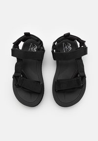 Musta sandaalit, joissa on säädettävät kangasremmit ja teksturoitu pohja pitävää otetta varten. Minimalistinen muotoilu, jossa on kevyt ja avara rakenne.