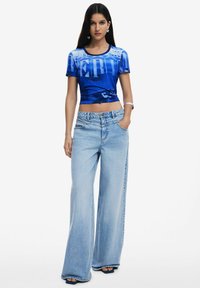 Blue cropped t-shirt with graphic design, paired with light blue wide-leg jeans. Smooth texture, casual fit, and minimal hardware details.