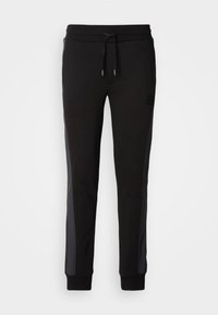 Pantalones deportivos negros con cintura elástica y cordón. Los paneles laterales en un tono más oscuro añaden textura. Los puños son elásticos. Detalle del logotipo presente.