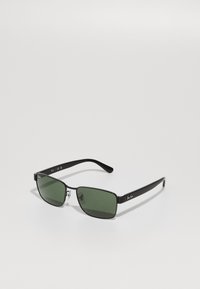 Ochelari de soare rectangulari negri cu lentile verzi, accente metalice pe ramă și logo-ul semnătură pe brațele ochelarilor. Design ușor și elegant.