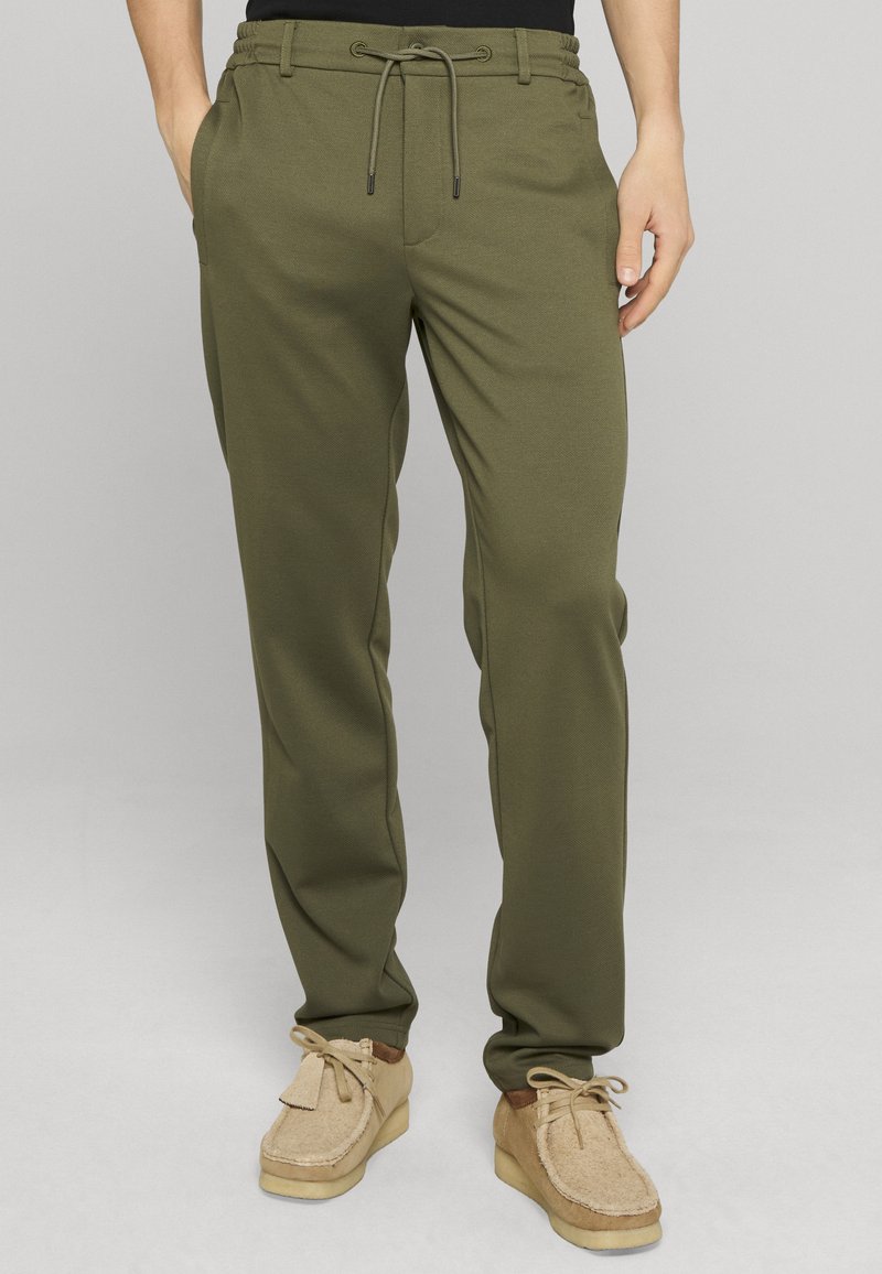 Pantalon de jogging vert olive en tissu doux, avec une taille élastique munie d'un cordon de serrage, des poches latérales et une coupe décontractée.
