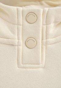 Colletto di polo bianco con due bottini rotondi in rilievo contrassegnati "POLO CLUB". Texture in cotone liscio con dettagli di cucitura visibili.