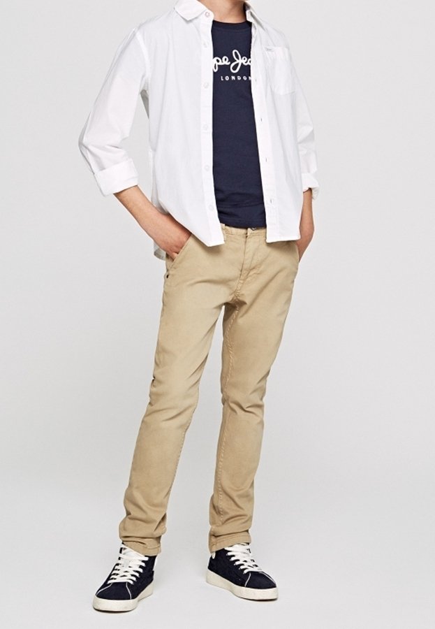 Lekka, biała koszula z guzikami noszona na granatowej koszulce, w zestawieniu z khaki spodniami oraz granatowymi trampkami z białymi podeszwami i sznurówkami.