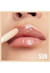 Gloss à lèvres à finition brillante et transparente, appliqué avec un applicateur ; couleur naturelle des lèvres en dessous, texture douce, avec l'étiquette "SUN" visible.