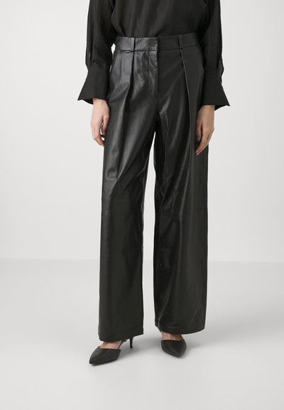 Pantaloni negri din piele, cu croi larg și pliuri, având o textură netedă și talie înaltă. Asortați cu pantofi cu toc subțire negri pentru un aspect elegant.