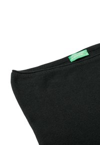 Černá texturovaná tkanina s jemným povrchem. Obsahuje zelenou visačku s nápisem "UNITED COLORS OF BENETTON" šitou do horního švu.