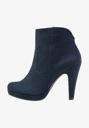 Bottine en daim bleu marine avec bout arrondi, semelle compensée et talon haut effilé, vue de côté.