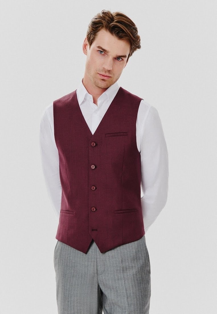 Burgundowy kamizelka z sześcioma guzikami i dopasowanym krojem, w połączeniu z białą koszulą i jasnoszarymi spodniami w paski.