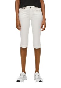 Valkoiset polvimittaiset farkut käännetyillä lahkeilla, valmistettu sileästä kankaasta, yhdistetty valkoisiin urheilukenkihin. Minimalistinen muotoilu, ei näkyviä koristeluja.